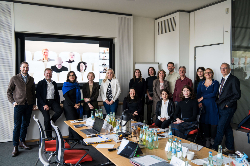 Gruppenbild mit 11 Frauen und 5 Männern von Beirat und Projekt. 4 Personen sind via Teams auf der Leinwand zu sehen.
